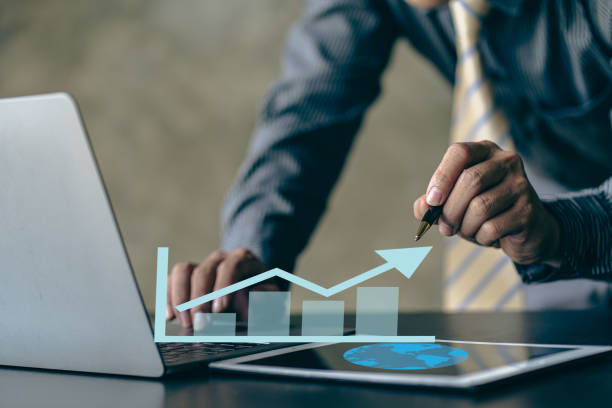 istock business growth, businessman hand typing note on keyboard Laptop with realistic enhanced technical charts and up arrows for traders analysis. Stocks, chart traders. Trading, investing. 1463814379