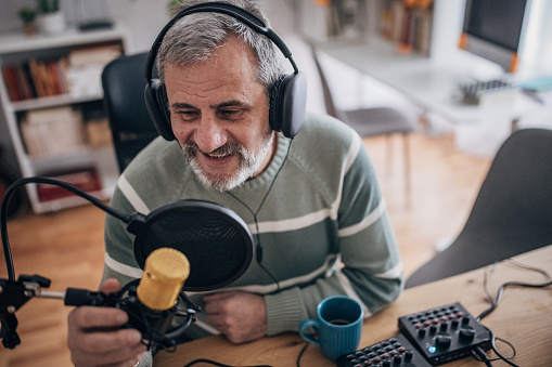 A senior male podcaster works alone