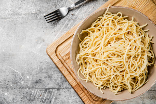 istock Full bowl with boiled spaghetti on a cutting board. 1463816681