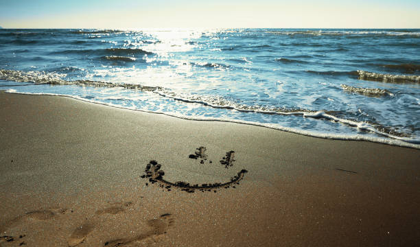 Smiley drawn on the sandy sea beach. stock photo
