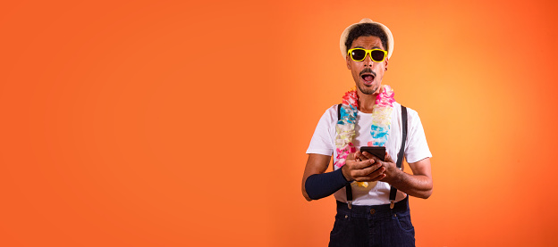Carnival Brazilian Outfit. Black Man With Carnival Costume Holding Mobile,  Isolated on Orange Background