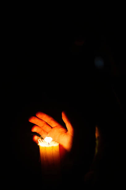istock Hand illuminated by the light of a candle. 1463818893