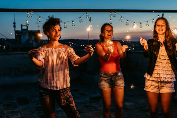 istock Three Female Friends Having A Party On The Rooftop With Sparklers 1463821179