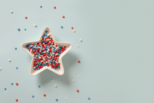 USA Independence Day concept. Red, white and blue star confetti in plate shape of star on blue background. Flat lay, top view, copy space. 4th of July.