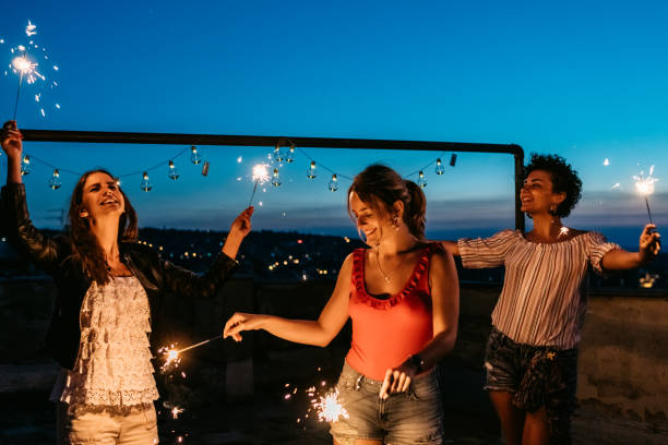istock Three Female Friends Having A Party On The Rooftop With Sparklers 1463821521