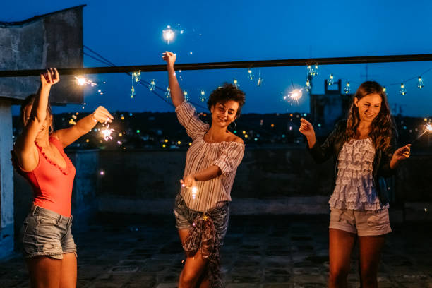 istock Three Female Friends Having A Party On The Rooftop With Sparklers 1463821592