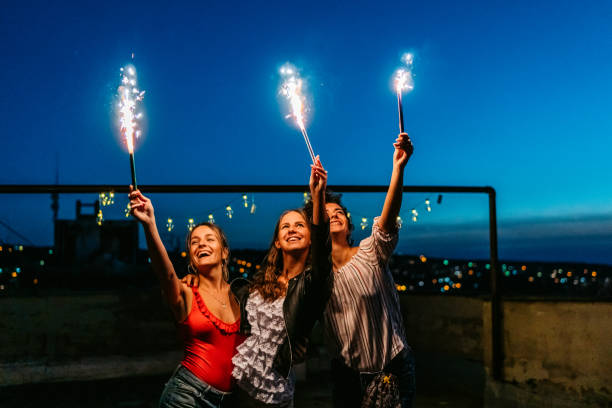 istock Three Female Friends Having A Party On The Rooftop With Firework Candles 1463821972