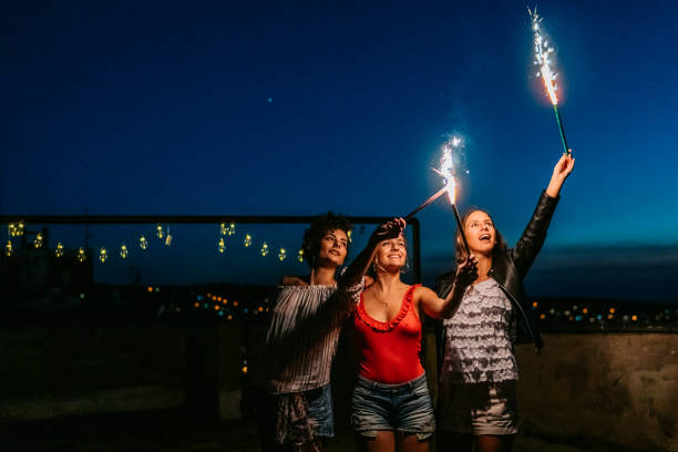 istock Three Female Friends Having A Party On The Rooftop With Firework Candles 1463822023