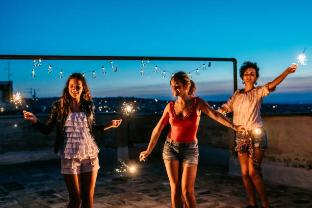 istock Three Female Friends Having A Party On The Rooftop With Sparklers 1463822044