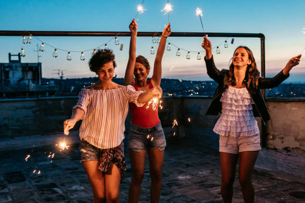 istock Three Female Friends Having A Party On The Rooftop With Sparklers 1463822071