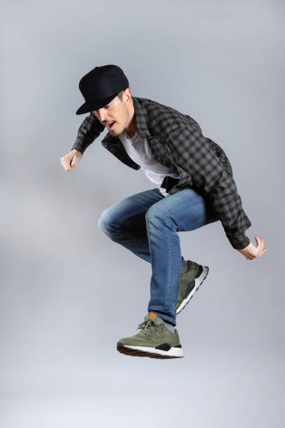 istock Happy Man jumps doing skater pose in grey background. 1463823699