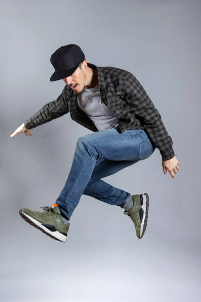 istock Happy Man jumps doing skater pose in grey background. 1463823729