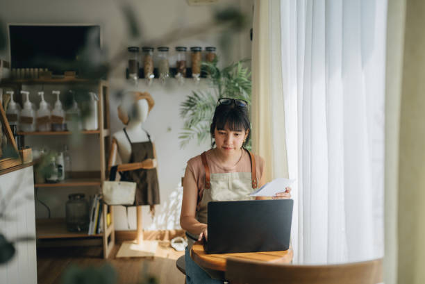 istock Young female small business owner making expenses at her store. 1463823969