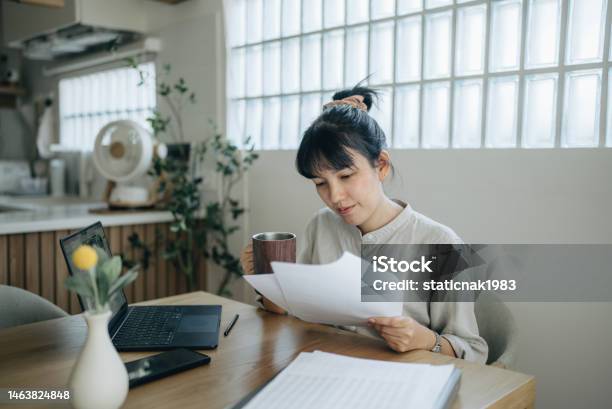 Asian Women Working With Invoices Calculates Expenses Doing Work At Home Stock Photo - Download Image Now