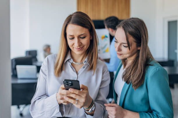 istock Two colleagues using mobile phone together in the office 1463824941