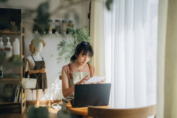 istock Young female small business owner making expenses at her store. 1463825020
