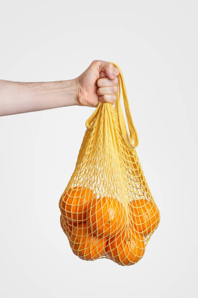 istock zero waste packaging. A shopping bag with oranges in a man's hand on a gray background 1463826794