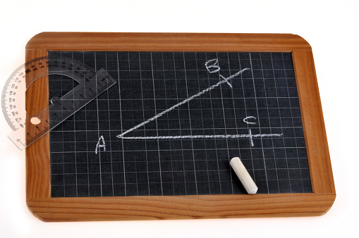 Measuring an angle with a protractor and a chalk on a school slate on a white background