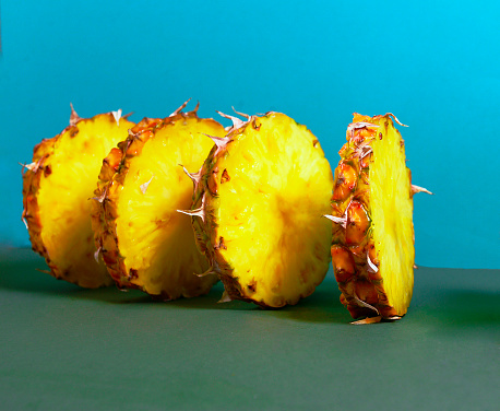 side view of a sliced pineapple as a textured background. Close-up Of Pineapple Slices On A Colored background. A bright composition that attracts attention and lifts the mood. design poster