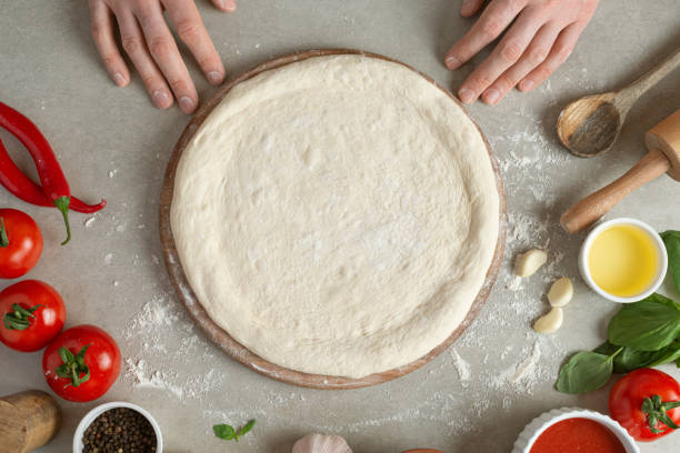 istock The process of making margarita pizza. Male hands, top view. Tomato paste with cheese. 1463828929