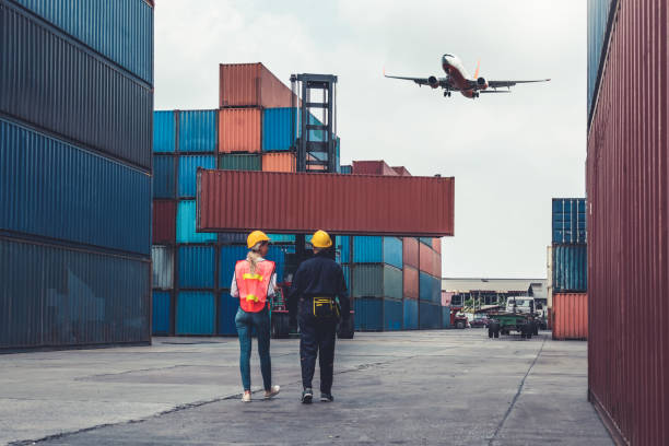 istock Industrial worker works with co-worker at overseas shipping container port . Logistics supply chain management and international goods export concept . 1463829104