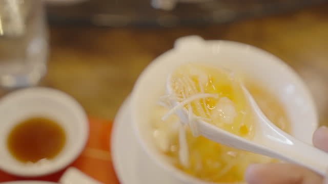 Clear Chinese style vegetable soup in a small bowl scooped by spoon