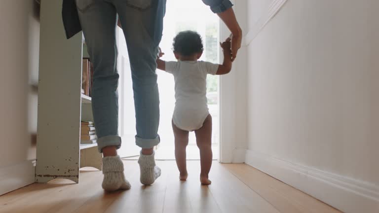 baby learning to walk toddler taking first steps with father helping infant teaching child at home