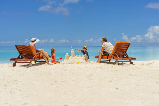 familienbau einer sandburg am strand im sommer - urlaubszeit - couple two parent family beach loving stock-fotos und bilder