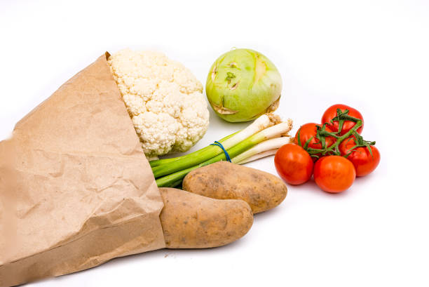 Shopping for fresh and healthy vegetables in a brown paper bag against white background stock photo