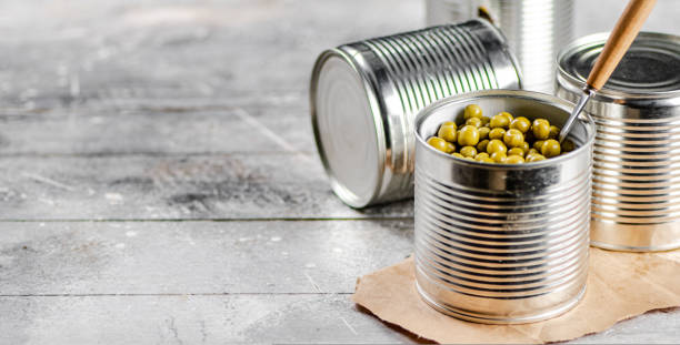 istock Open tin can with canned green peas with a spoon. 1463835492