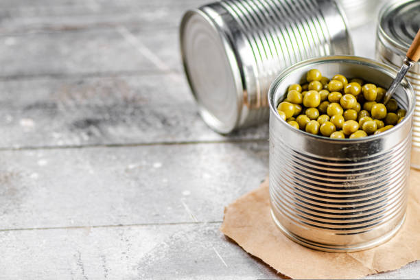 istock Open tin can with canned green peas with a spoon. 1463835737