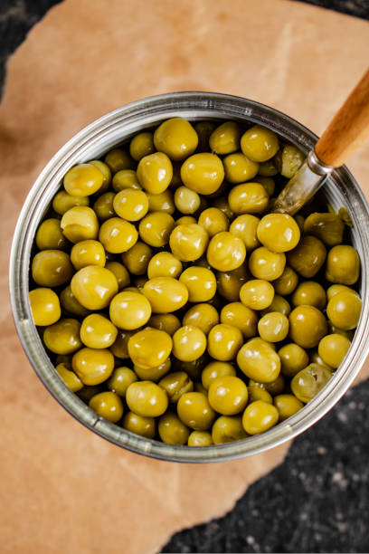 istock An open tin can with canned green peas on paper. 1463836698