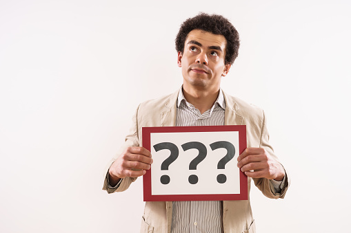 Image of confused businessman  showing paper with question marks.