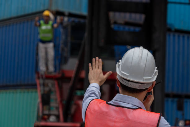 istock Industrial worker works with co-worker at overseas shipping container yard . Logistics supply chain management and international goods export concept . 1463842066