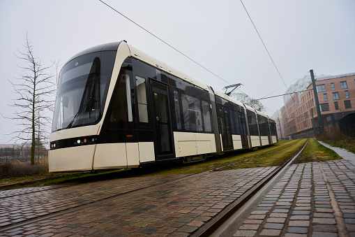 Lightrail car in Odense city a hazy day in February. Busy road has been replaced by buildings and lightrail transportation.