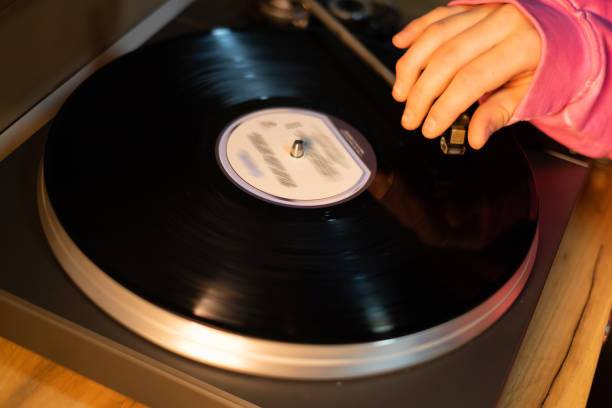 the hand that lowers the needle on the gramophone record the hand drops the needle on the spinning record. musical minimalist concept record player needle stock pictures, royalty-free photos & images