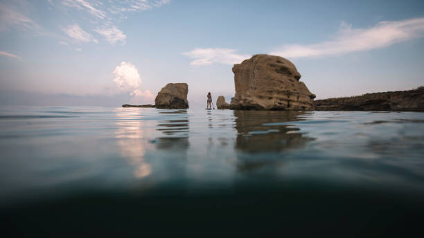 istock Woman paddleboarding through passage between sea rocks 1463847207