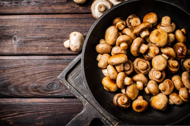 Fragrant homemade fried mushrooms in a frying pan on a cutting board. On a wooden background. High quality photo