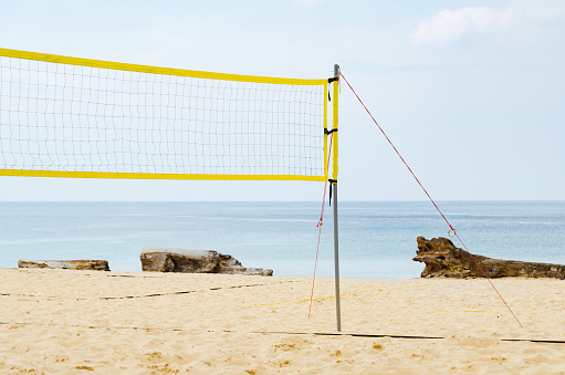 Volleyball net over clean sand beach and ocean background with blue sky