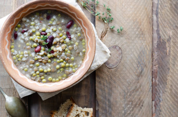 Bean soup in a ceramic bowl with a sprig of thyme on a wooden table. A mix of red beans, lentils and peas. The concept of vegetarian food. Rustic style. Horizontal orientation. Copy space. Top view stock photo