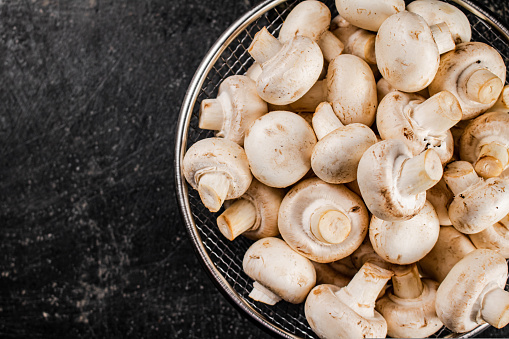 Fresh mushrooms in a colander. On a black background. High quality photo