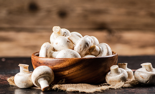 A wooden plate full of fresh mushrooms. On a wooden background. High quality photo