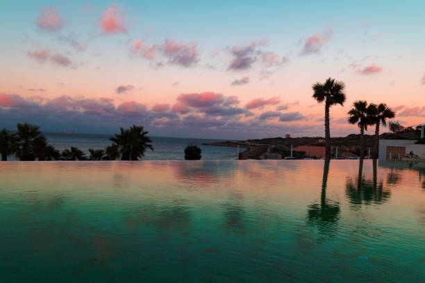 Endless pool at sunset, with palm trees, in a Maltese hotel. with orange clouds. golden hour. Sunset