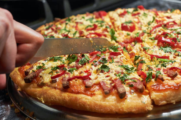 istock Cutting pizza into pieces in close-up. Vegetable pizza with cheese 1463859749