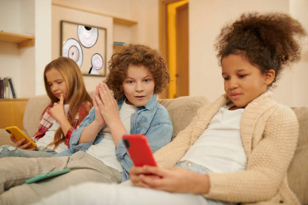 istock Kids sitting on the sofa with gadgets in hands and looking involved 1463863124
