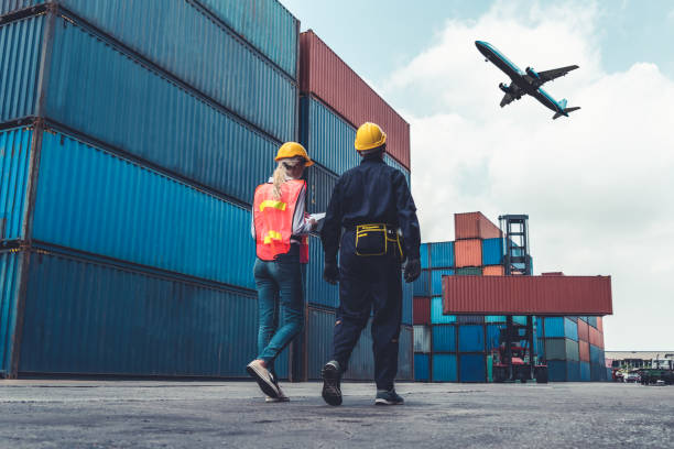 istock Industrial worker works with co-worker at overseas shipping container port . Logistics supply chain management and international goods export concept . 1463863131