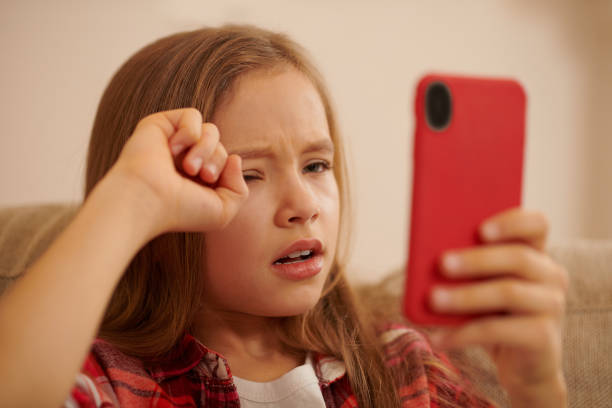 istock Cute blonde girl with a device in hands looking involved while watching something 1463863756