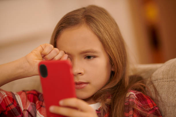 istock Cute blonde girl with a device in hands looking involved while watching something 1463863791