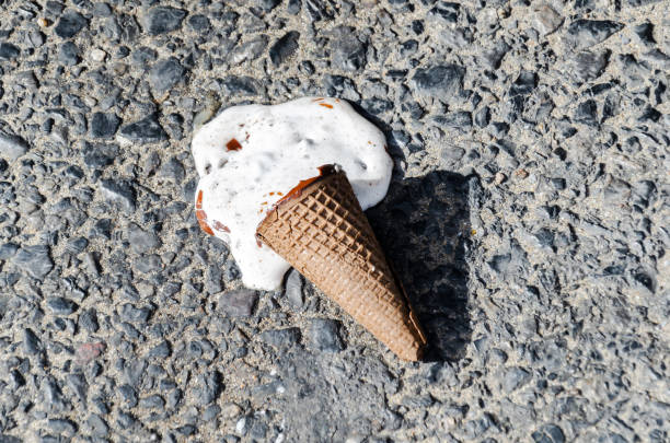 melted ice cream on sidewalk on hot summer day. ice cream in cone fell and melted. selective focus
