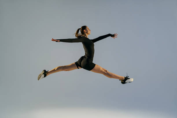 istock Sporty girl jumping doing split leap in air with joyful expression. Flexible and weightless concept 1463865889